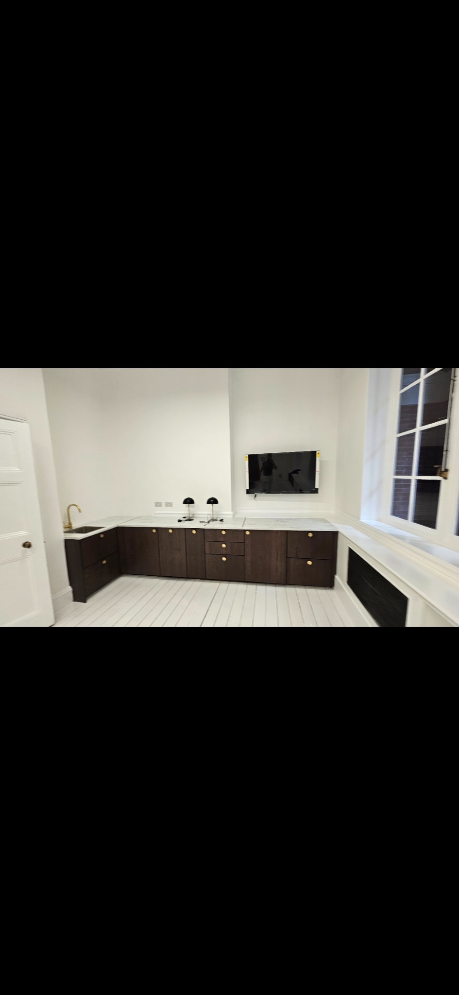 Dark fitted kitchen cabinetry and marble worktop